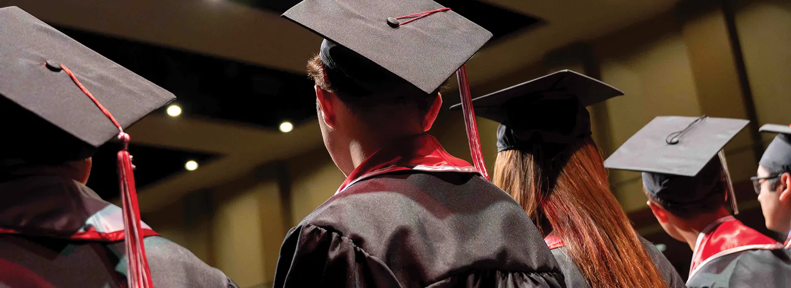 Graduates are on stage in the lights of the Performing Arts Center.